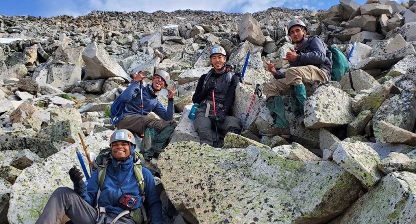 A group of people wearing safety gear sit among large rocks